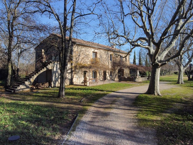 Mas Provençale avec un chemin, entourée d'arbres et de verdure.