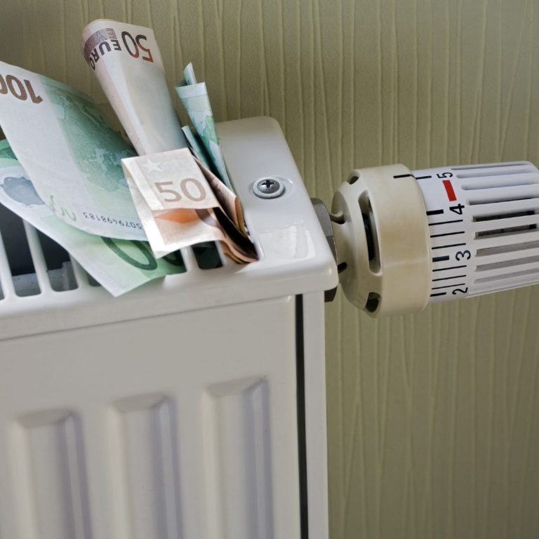 Billets de banque dépassant d'un radiateur sur un mur clair.