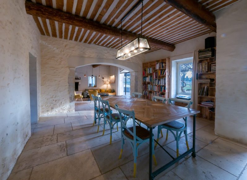 Salle à manger spacieuse avec une grande table en bois et chaises colorées.